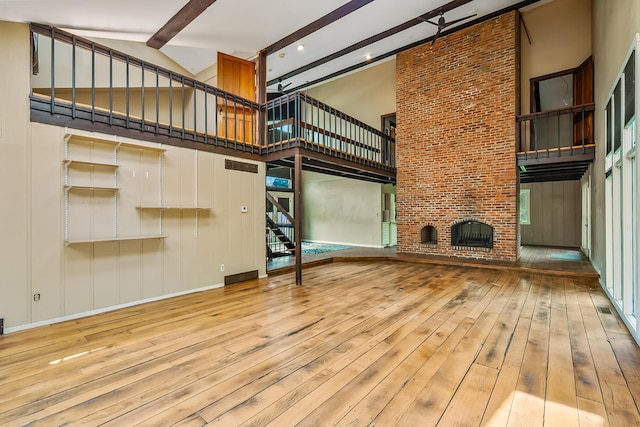 933 Creek Run Ct, Westerville, OH 43081 - unfurnished living room with a towering ceiling, beam ceiling, wood-type flooring, a fireplace, and stairs