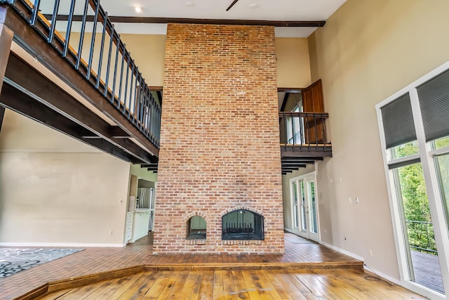 933 Creek Run Ct, Westerville, OH 43081 - unfurnished living room with a high ceiling, hardwood / wood-style floors, a brick fireplace, and stairway