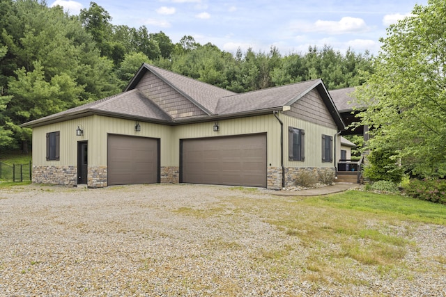 19694 State Route 60, Warsaw, OH 43844 - view of side of home featuring stone siding, a shingled roof, gravel driveway, and an attached garage