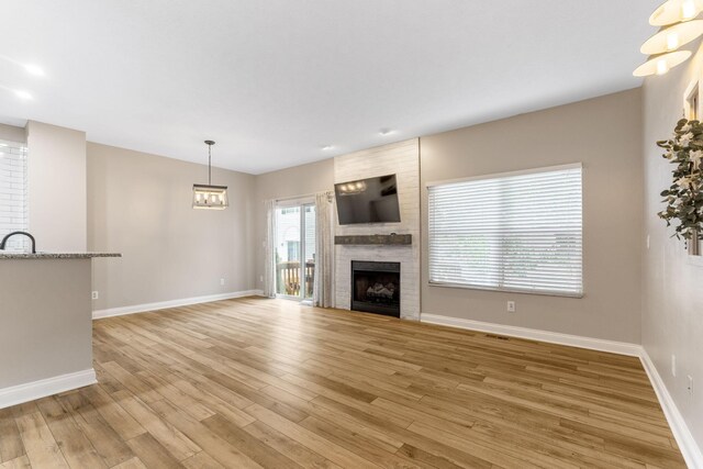 3984 Hill Park Rd, Hilliard, OH 43026 - unfurnished living room featuring light wood-style flooring, a large fireplace, and a chandelier