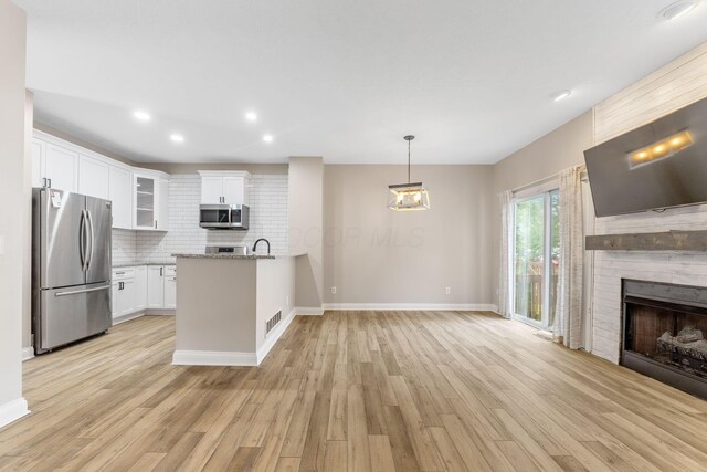 3984 Hill Park Rd, Hilliard, OH 43026 - kitchen featuring appliances with stainless steel finishes, a peninsula, backsplash, light wood-type flooring, and glass insert cabinets