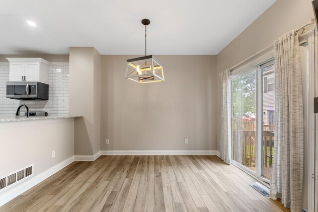 3984 Hill Park Rd, Hilliard, OH 43026 - unfurnished dining area with light wood finished floors and a chandelier