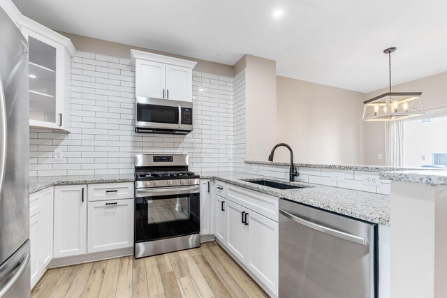3984 Hill Park Rd, Hilliard, OH 43026 - kitchen featuring appliances with stainless steel finishes, a peninsula, a chandelier, white cabinetry, and decorative backsplash