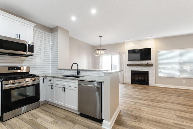 3984 Hill Park Rd, Hilliard, OH 43026 - kitchen with stainless steel appliances, a peninsula, open floor plan, decorative backsplash, and white cabinetry