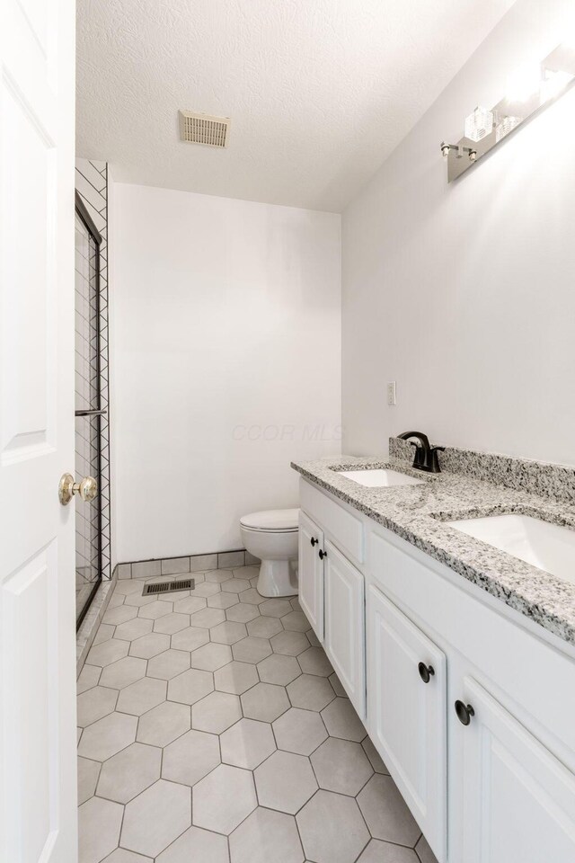 3984 Hill Park Rd, Hilliard, OH 43026 - full bath featuring double vanity, a shower, a textured ceiling, and tile patterned flooring