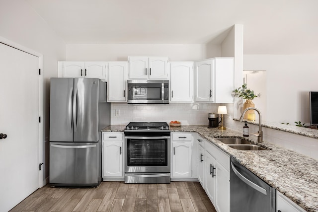 3776 Secretariat Ct, Columbus, OH 43221 - kitchen with stainless steel appliances, white cabinetry, light stone counters, light wood-type flooring, and backsplash