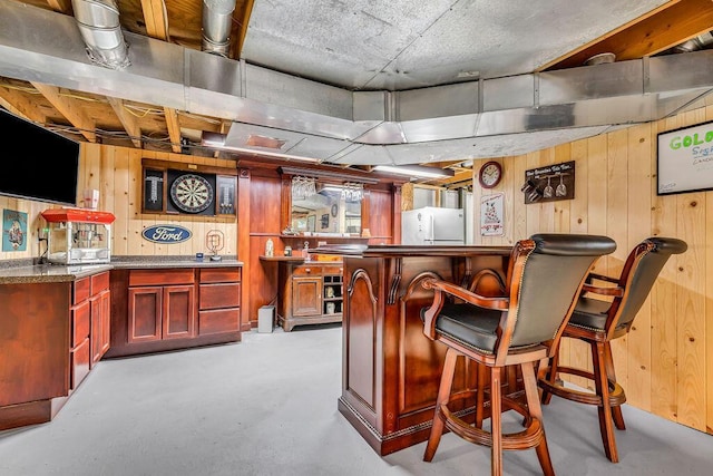 13283 Clover Valley Rd, Croton, OH 43013 - indoor dry bar with wood walls, fridge, and concrete flooring