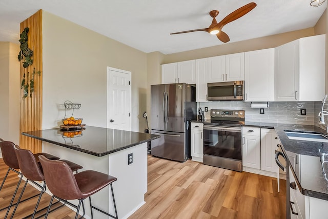 3956 Darby Park Rd, Hilliard, OH 43026 - kitchen with appliances with stainless steel finishes, light wood-type flooring, a ceiling fan, and a kitchen breakfast bar