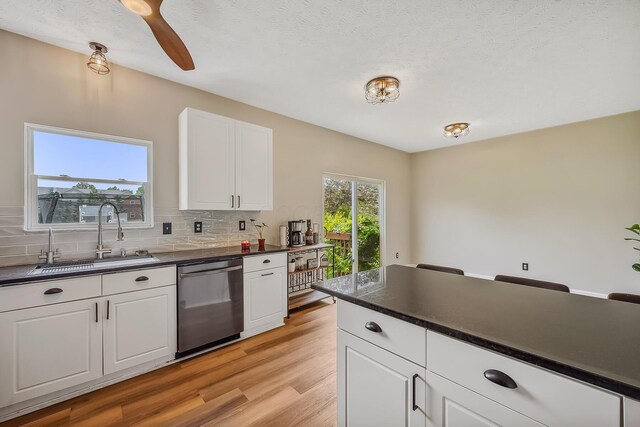 3956 Darby Park Rd, Hilliard, OH 43026 - kitchen with dishwasher, dark countertops, light wood finished floors, tasteful backsplash, and white cabinetry