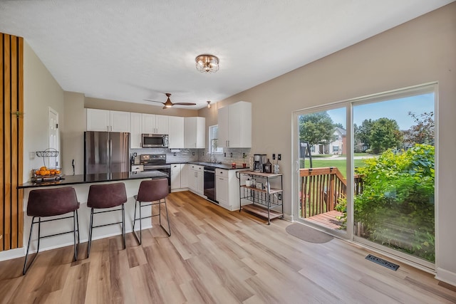 3956 Darby Park Rd, Hilliard, OH 43026 - kitchen with stainless steel appliances, a breakfast bar area, light wood-type flooring, a peninsula, and white cabinets