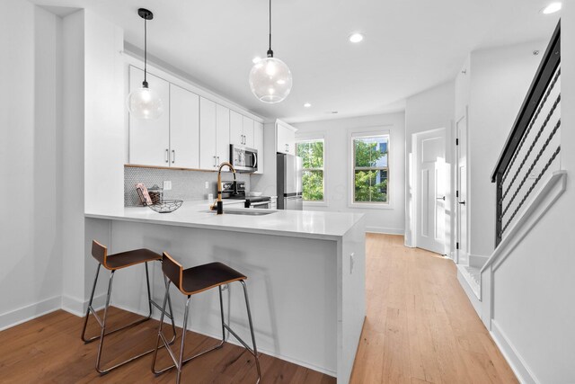 91 W Town St, Columbus, OH 43215 - kitchen with appliances with stainless steel finishes, light countertops, backsplash, a peninsula, and hanging light fixtures
