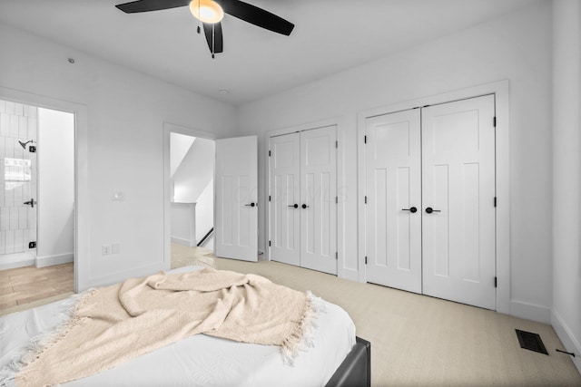 91 W Town St, Columbus, OH 43215 - bedroom featuring multiple closets, connected bathroom, ceiling fan, and light colored carpet