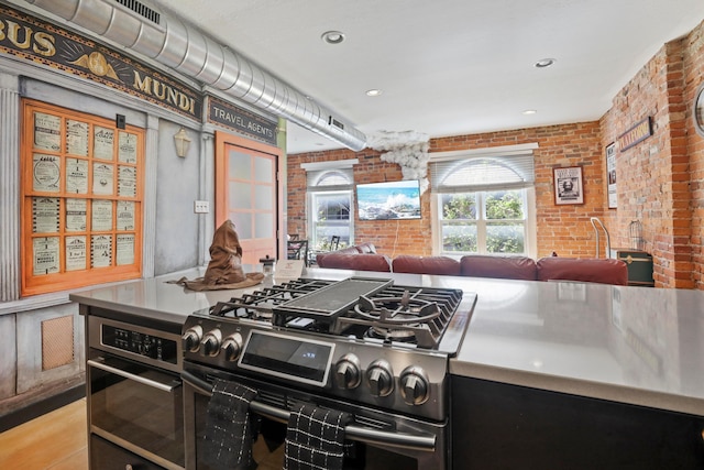 974 N High St Unit B, Columbus, OH 43201 - kitchen featuring stainless steel range with gas stovetop, brick wall, oven, light wood-style floors, and recessed lighting