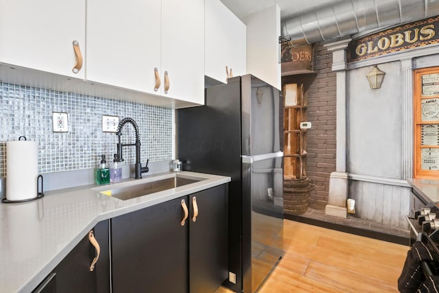 974 N High St Unit B, Columbus, OH 43201 - kitchen featuring freestanding refrigerator, white cabinets, light countertops, light wood-type flooring, and decorative backsplash