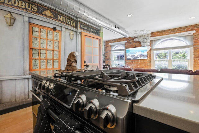 974 N High St Unit B, Columbus, OH 43201 - detailed view of black range with gas stovetop, brick wall, wood finished floors, and recessed lighting