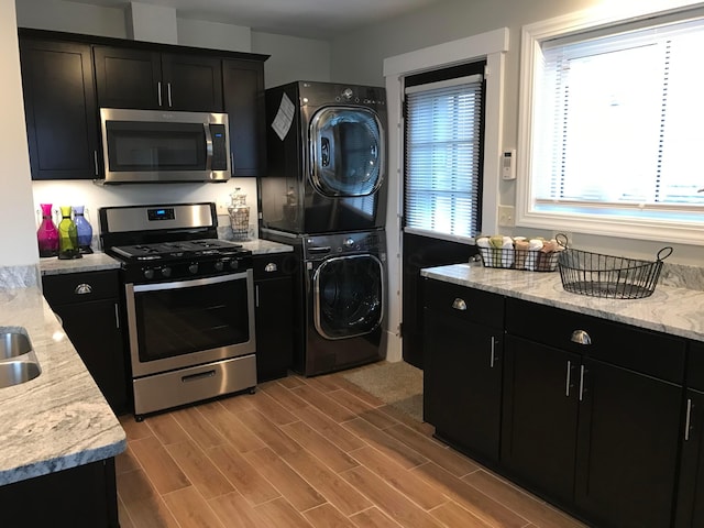 1427 Grogan Ave, Columbus, OH 43211 - kitchen featuring stainless steel appliances, stacked washer / drying machine, dark cabinetry, and wood finished floors
