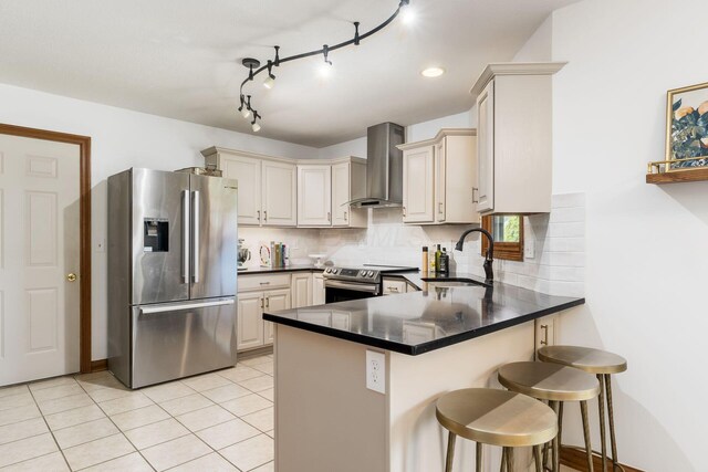 7949 Bluefield St NW, Canal Winchester, OH 43110 - kitchen featuring appliances with stainless steel finishes, wall chimney range hood, a peninsula, cream cabinets, and decorative backsplash