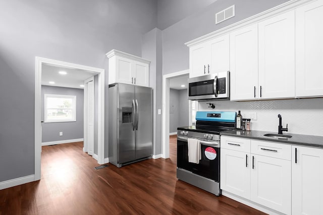 172 Jefferson St, Mount Sterling, OH 43143 - kitchen featuring appliances with stainless steel finishes, dark countertops, dark wood-style flooring, backsplash, and white cabinets