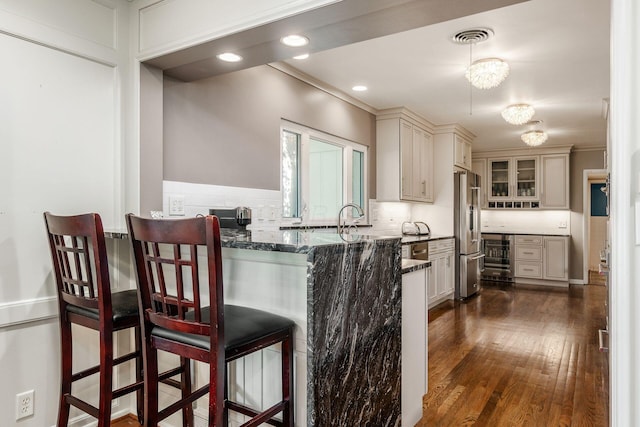 207 Ashbourne Rd, Bexley, OH 43209 - kitchen with freestanding refrigerator, a kitchen bar, dark stone countertops, beverage cooler, and dark wood-type flooring