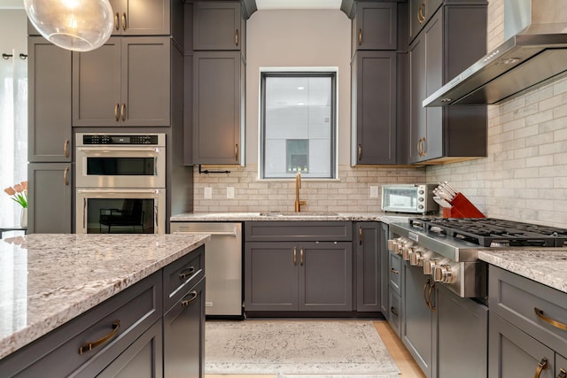 2891 Kobuk Dr Unit 301, Columbus, OH 43228 - kitchen with wall chimney range hood, appliances with stainless steel finishes, backsplash, light stone countertops, and gray cabinets
