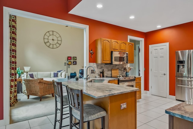 1554 Hanover Rd, Delaware, OH 43015 - kitchen with stainless steel appliances, light tile patterned floors, a kitchen bar, a peninsula, and brown cabinets
