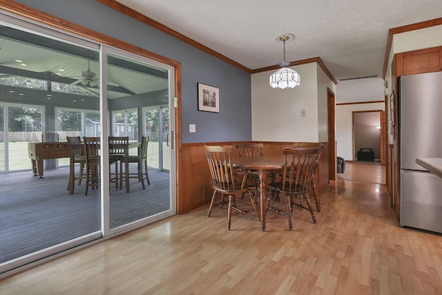9840 Buckeye Dr, Huntsville, OH 43324 - dining space featuring light wood finished floors, wainscoting, ornamental molding, and a ceiling fan