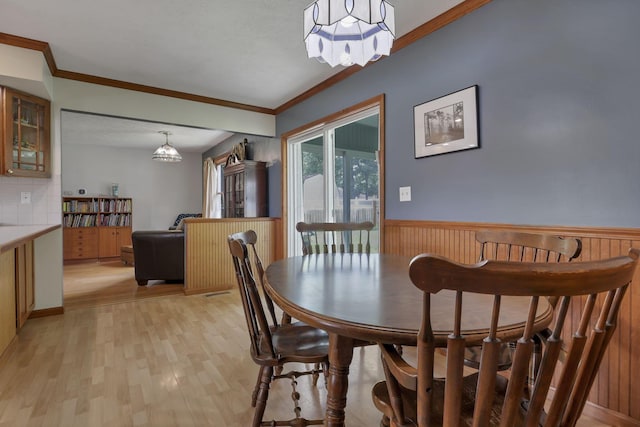 9840 Buckeye Dr, Huntsville, OH 43324 - dining room with light wood-style flooring, crown molding, a chandelier, and wainscoting