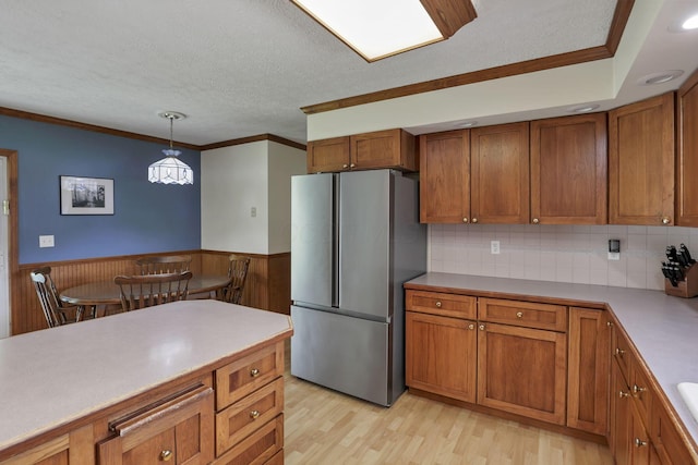 9840 Buckeye Dr, Huntsville, OH 43324 - kitchen featuring freestanding refrigerator, brown cabinetry, a textured ceiling, light wood-style flooring, and wainscoting