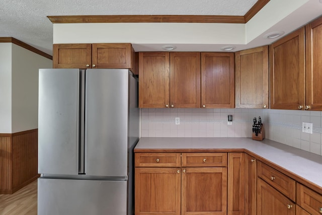 9840 Buckeye Dr, Huntsville, OH 43324 - kitchen with freestanding refrigerator, crown molding, brown cabinets, a textured ceiling, and light countertops