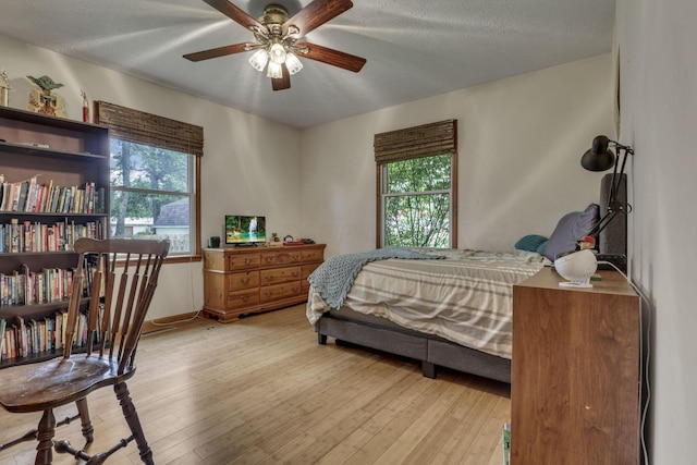 9840 Buckeye Dr, Huntsville, OH 43324 - bedroom with light wood finished floors, multiple windows, ceiling fan, and a textured ceiling