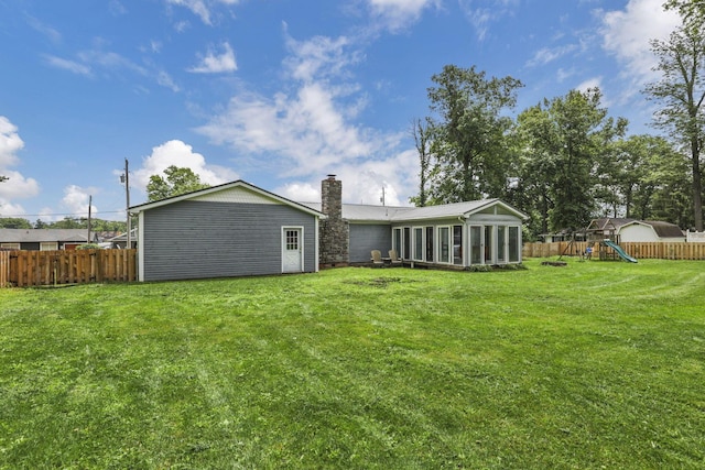 9840 Buckeye Dr, Huntsville, OH 43324 - back of property featuring a chimney, a playground, a sunroom, and a fenced backyard