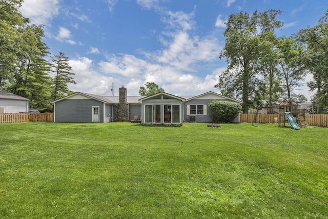 9840 Buckeye Dr, Huntsville, OH 43324 - back of property with a chimney, a playground, a fenced backyard, and a sunroom