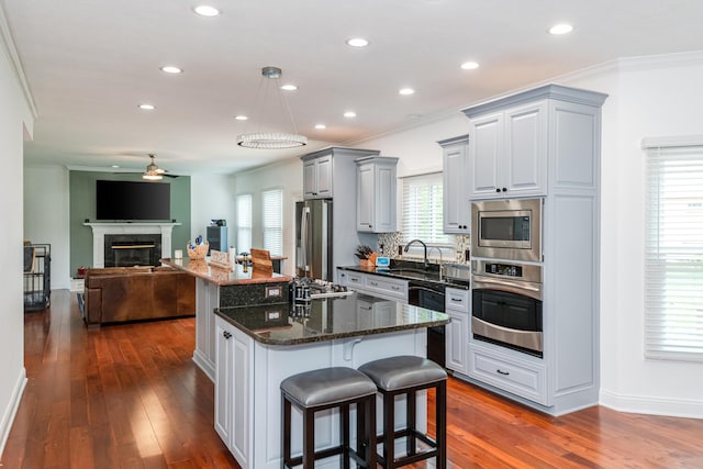 9950 Stonemead Way, Dayton, OH 45458 - kitchen featuring appliances with stainless steel finishes, a ceiling fan, a kitchen bar, open floor plan, and dark wood finished floors