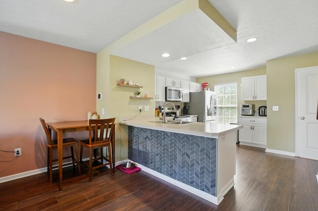 5346 Calypso Cascades Dr, Dublin, OH 43016 - kitchen with stainless steel appliances, a peninsula, white cabinets, dark wood-style flooring, and recessed lighting