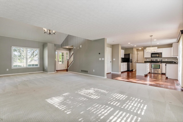 7341 Clancy Way, Westerville, OH 43082 - unfurnished living room with light colored carpet, a chandelier, stairway, and recessed lighting