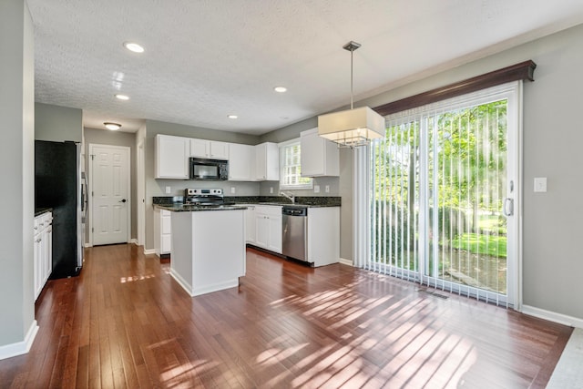 7341 Clancy Way, Westerville, OH 43082 - kitchen featuring appliances with stainless steel finishes, dark wood-style floors, dark countertops, a kitchen island, and white cabinets