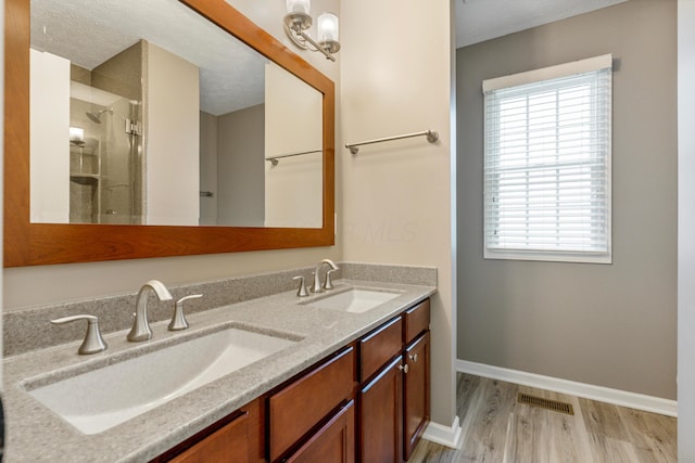 7341 Clancy Way, Westerville, OH 43082 - full bathroom featuring double vanity, wood finished floors, healthy amount of natural light, an enclosed shower, and a textured ceiling