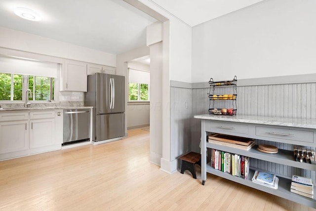 405 N Union St, Galion, OH 44833 - kitchen featuring appliances with stainless steel finishes, light wood-type flooring, plenty of natural light, light stone counters, and wainscoting