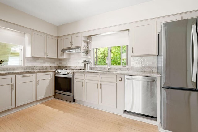 405 N Union St, Galion, OH 44833 - kitchen featuring appliances with stainless steel finishes, under cabinet range hood, tasteful backsplash, light wood finished floors, and light stone counters