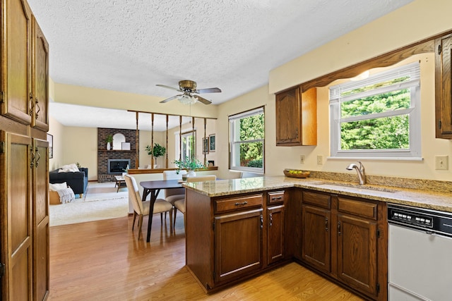 9 Intermeadows Way, Powell, OH 43065 - kitchen with white dishwasher, a brick fireplace, light wood finished floors, a peninsula, and ceiling fan