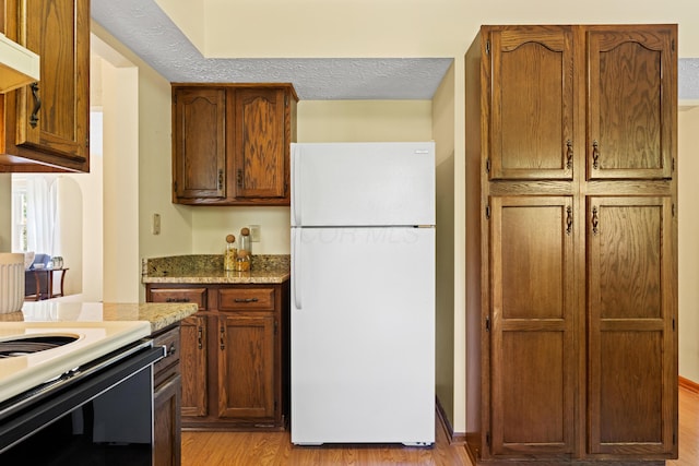 9 Intermeadows Way, Powell, OH 43065 - kitchen featuring white appliances, light wood-type flooring, ventilation hood, and brown cabinetry
