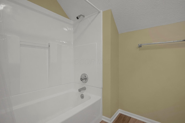764 Towne Krier Ct, Newark, OH 43055 - full bathroom featuring wood finished floors, washtub / shower combination, vaulted ceiling, and a textured ceiling