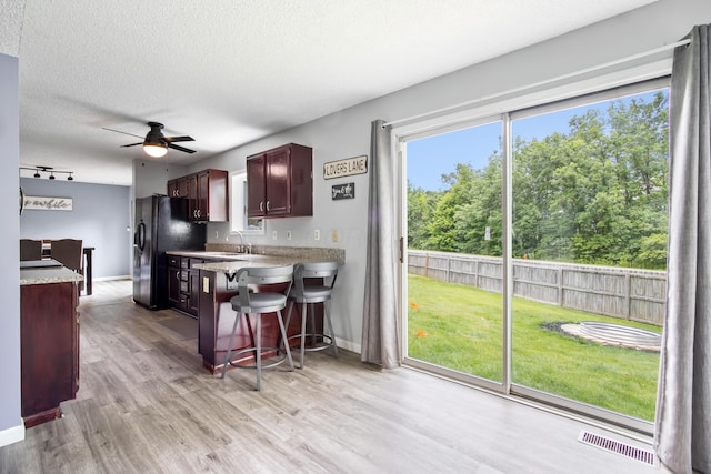 3124 Hillrose Dr, Hilliard, OH 43026 - kitchen with freestanding refrigerator, ceiling fan, light wood finished floors, a kitchen bar, and a textured ceiling