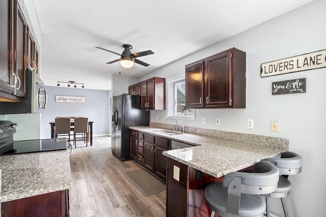 3124 Hillrose Dr, Hilliard, OH 43026 - kitchen with black fridge with ice dispenser, ceiling fan, a kitchen bar, a peninsula, and light wood-style floors