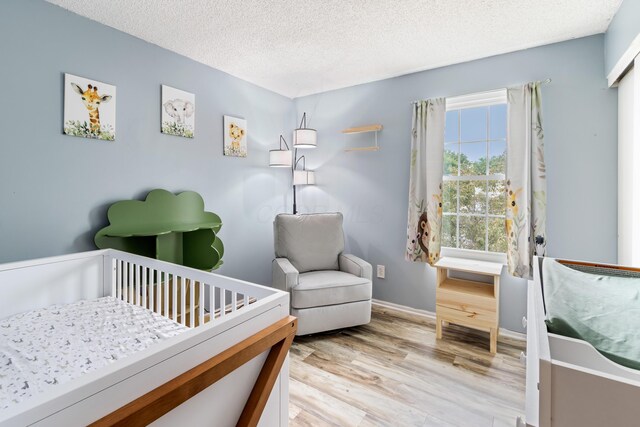 3124 Hillrose Dr, Hilliard, OH 43026 - bedroom with a nursery area, a textured ceiling, and light wood-style floors