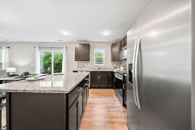1364 Robinof Dr, Grove City, OH 43123 - kitchen with appliances with stainless steel finishes, a center island, light wood finished floors, light stone countertops, and dark brown cabinets
