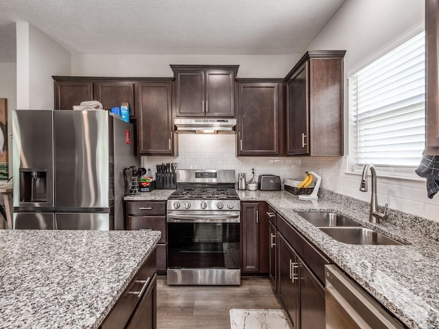326 Mannaseh Dr W, Granville, OH 43023 - kitchen featuring appliances with stainless steel finishes, under cabinet range hood, wood finished floors, light stone counters, and a textured ceiling