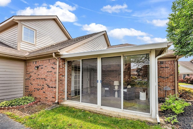 9460 Clermont Cir, Powell, OH 43065 - view of side of home with brick siding, a sunroom, and a shingled roof