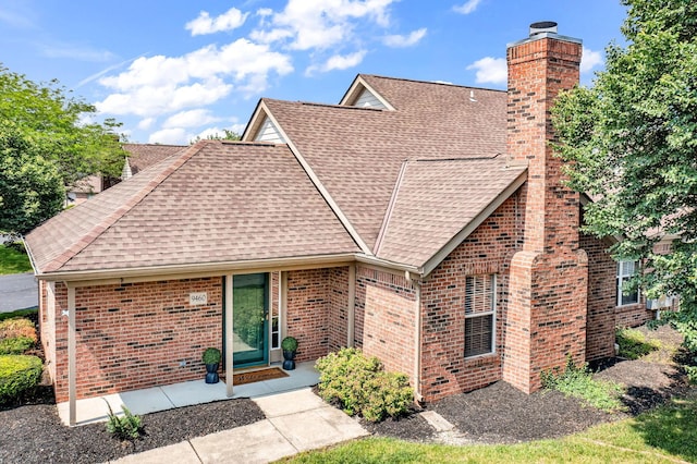 9460 Clermont Cir, Powell, OH 43065 - view of front of house featuring roof with shingles, a chimney, and brick siding