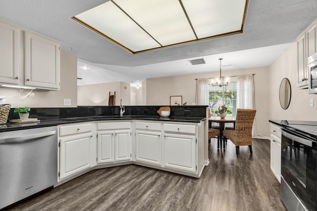 9460 Clermont Cir, Powell, OH 43065 - kitchen with appliances with stainless steel finishes, dark wood-type flooring, a chandelier, a peninsula, and dark countertops